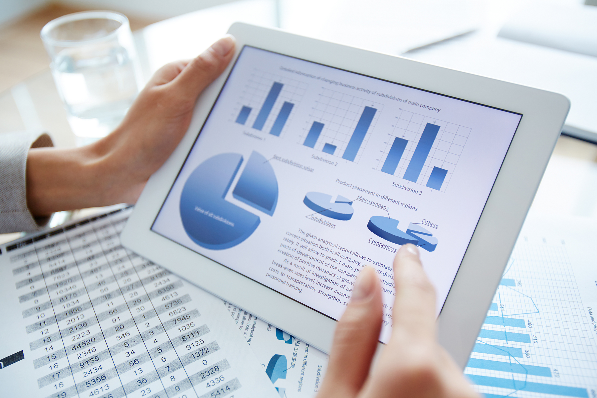 Descriptive image: hands holding a tablet with graphs and charts displayed